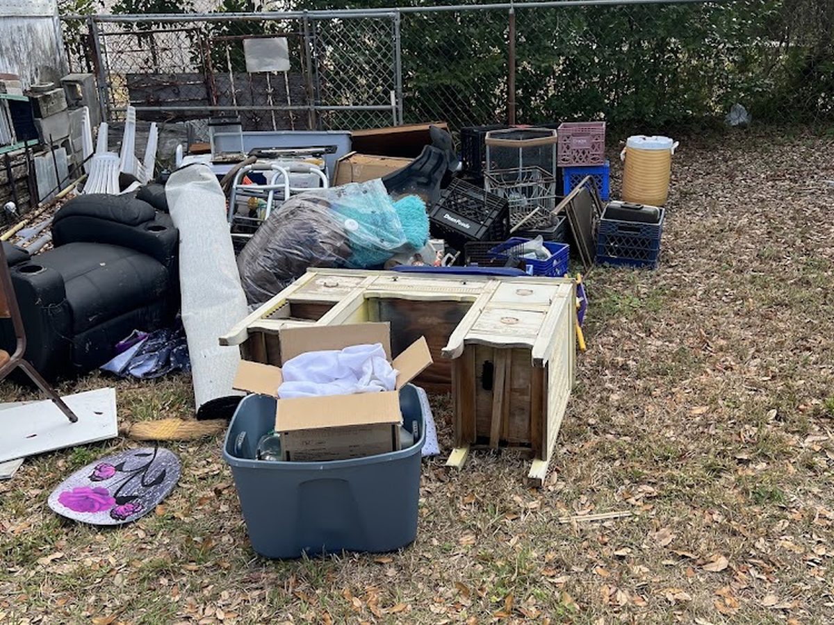 Backyard piled with old furniture and totes